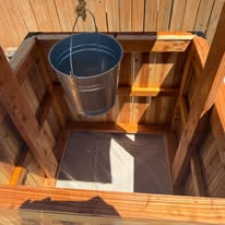 Overhead detail of the inside of a wishing well planter showing the bucket, rope and protective liner.