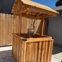 Wishing well photographed from the side showing the angled roof overhang and deep planter box.