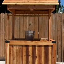 Sunlit cedar wishing well with the bucket lowered into the planter box.